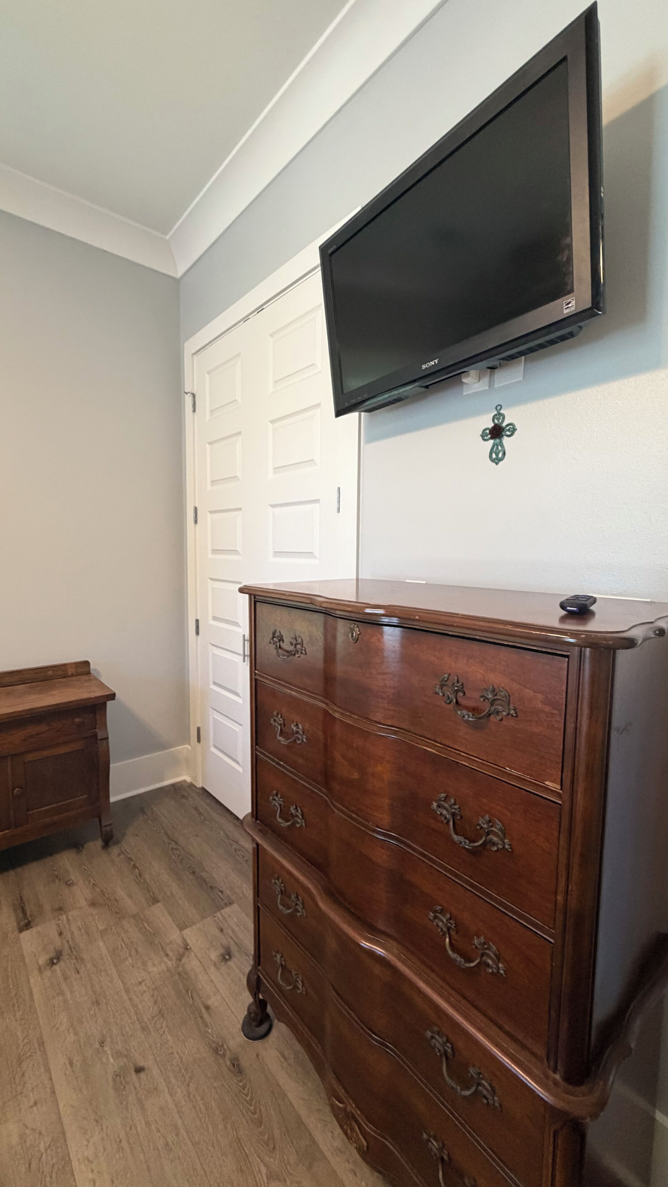 Ein Zimmer mit einem Holzkasten, einem an der Wand befestigten Fernseher und einer weißen Tür.