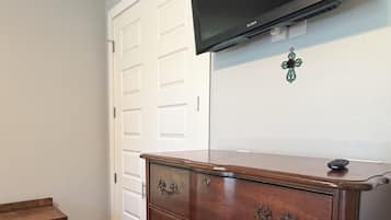 Ein Zimmer mit einem Holzkasten, einem an der Wand befestigten Fernseher und einer weißen Tür.