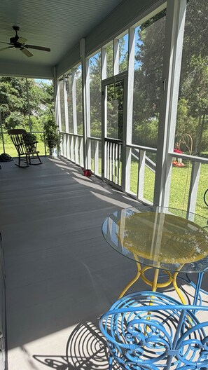 A covered porch with a ceiling fan, a glass table, and blue chairs. - Beautiful 2-bedroom, newly built home situated in historic Old Town Bay St Louis (Bay St. Louis)