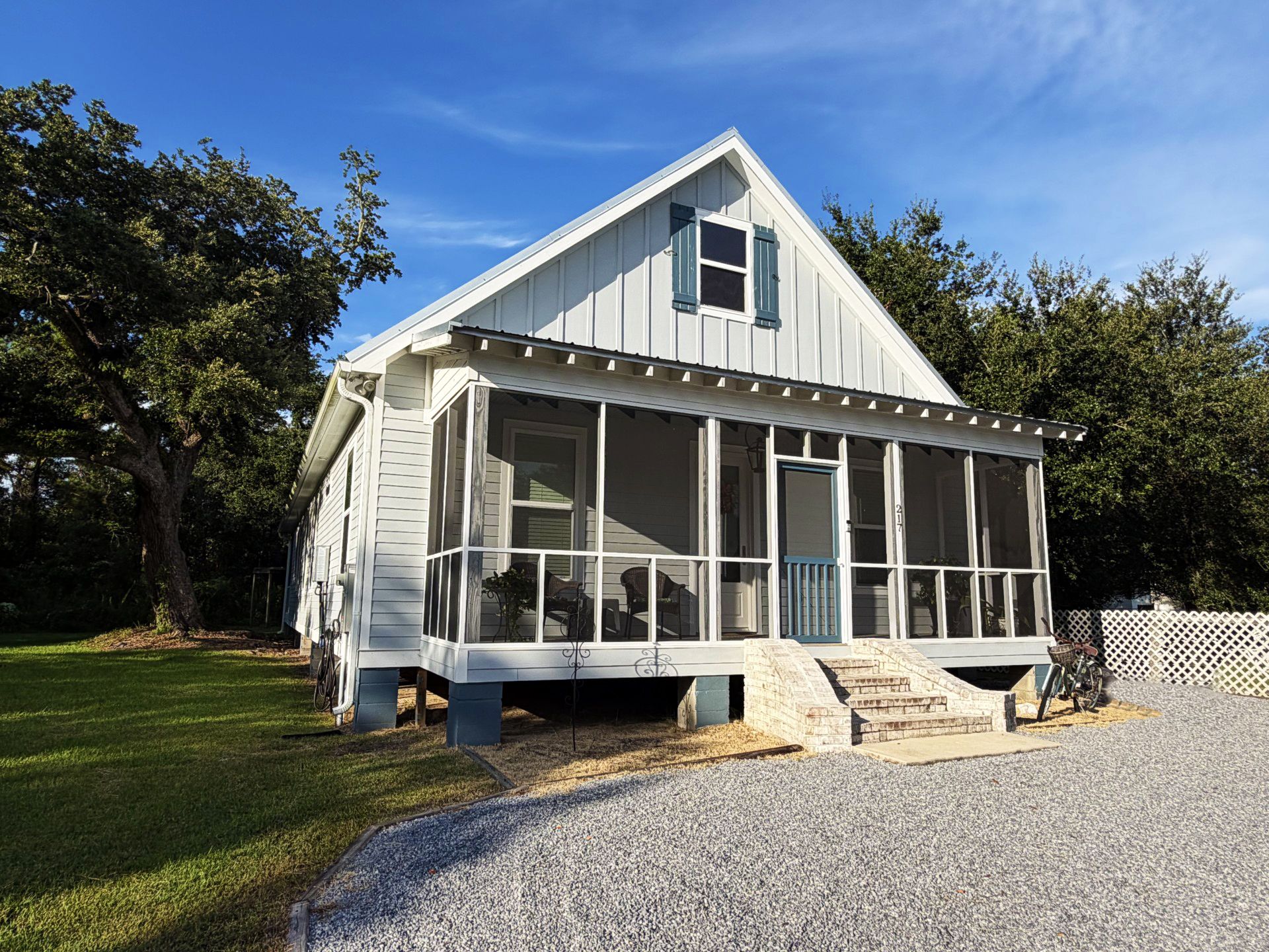 A single-story house with a porch, large windows, and a small staircase leading to the entrance.