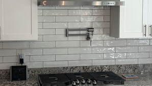 A kitchen with white cabinets, a stainless steel range hood, a granite countertop, and a gas stove.