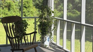 A covered porch with a rocking chair and a potted plant.