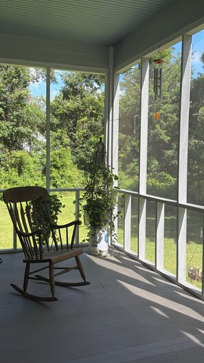 A covered porch with a rocking chair and a potted plant. - Beautiful 2-bedroom, newly built home situated in historic Old Town Bay St Louis (Bay St. Louis)