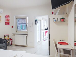 Una sala de estar moderna con comedor, un radiador, una ventana con vistas y un televisor montado en la pared.