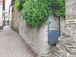 Una estrecha calle empedrada con un muro de piedra a un lado y una reja metálica al otro.