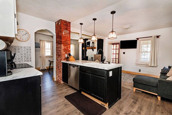 A modern kitchen with a central island, black cabinets, and hanging pendant lights.