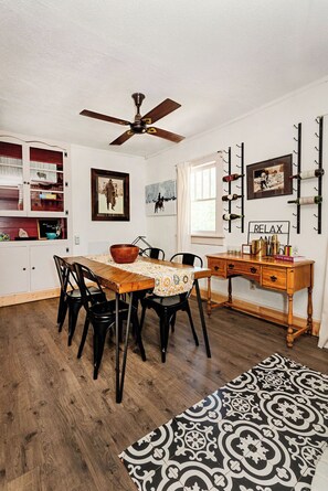 Un coin repas avec une table en bois, des chaises et un ventilateur de plafond.