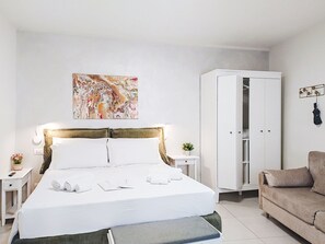 Ein Hotelzimmer mit einem Bett, einem Kleiderschrank, einer Sitzecke und einem an der Wand hängenden Kunstwerk.