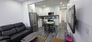 Eine moderne Küche mit weißen Schränken, einem Edelstahlkühlschrank und einem Essbereich mit Tisch und Stühlen.