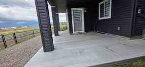 Eine überdachte Veranda mit Betonboden, einer Tür und einem Fenster.