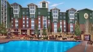 Un hotel con piscina, fachada de piedra y varias ventanas.