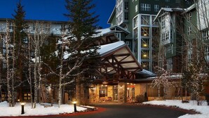 Un hotel con una entrada destacada, grandes ventanales y un paisaje cubierto de nieve.