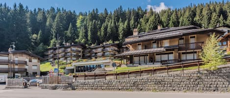 A mountain resort with multi-story buildings, balconies, and a stone retaining wall.