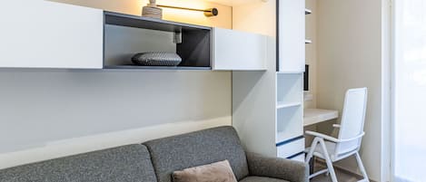 Una sala de estar moderna con un sofá gris, una silla blanca y estanterías empotradas con objetos decorativos.