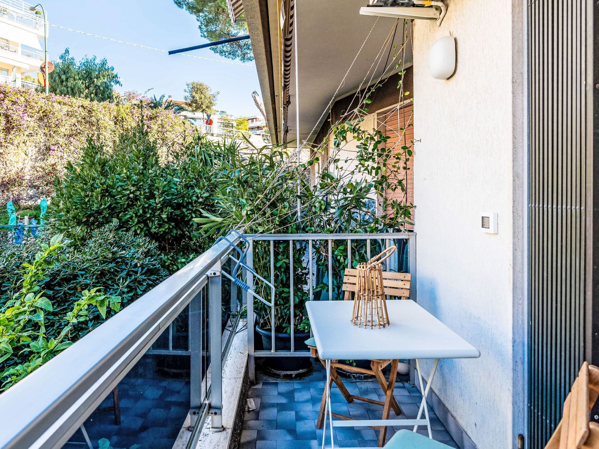 Ein Balkon mit Tisch und Stühlen, umgeben von Grünpflanzen und einem Geländer.