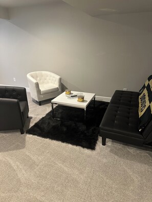 A living room with a white armchair, a black sofa, a coffee table with two candles, and a black furry rug. - Charming townhome in gorgeous Milliken Colorado with easy access to relaxation . (Milliken)