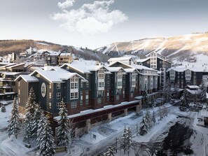 Ett snötäckt hotell med flera byggnader, en skidbacke i bakgrunden och ett bergigt landskap.