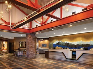 Eine Hotelhalle mit einer Rezeption, einer Sitzecke und einem großen Wandgemälde.