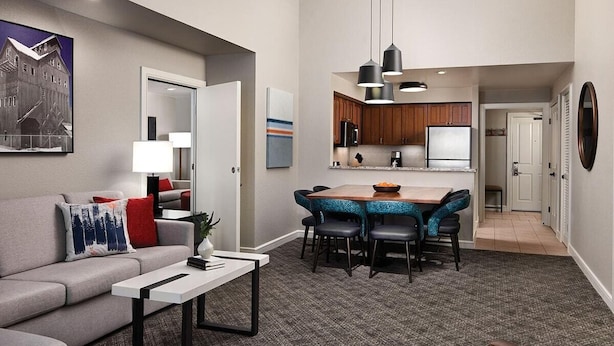 A modern living room with a grey sofa, a white coffee table, and a dining area with a wooden table and blue chairs. - 2 Bedroom Villa at Marriott MountainSide Resort (Park City)