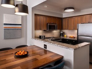 Eine moderne Küche mit Holzschränken, Edelstahlgeräten, einer Granitarbeitsplatte und Pendelleuchten.