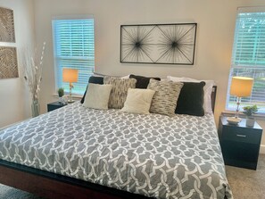 A neatly arranged bedroom with a patterned bedspread, decorative wall art, and bedside lamps. - Quiet, gated, near Towncenter Market st (Spring)