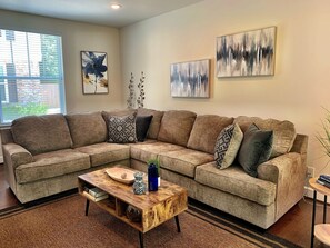 A sectional sofa with patterned cushions, a wooden coffee table, and abstract wall art. - Quiet, gated, near Towncenter Market st (Spring)