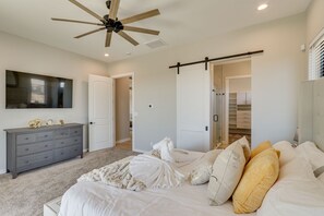 A bedroom with a bed, a dresser, a ceiling fan, and a walk-in closet. - Apache Junction Vacation Rental Heated Pool, Mountain Views, Pet-Friendly Home (Apache Junction)