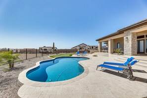 A swimming pool with a curved design, surrounded by a paved patio with lounge chairs. - Apache Junction Vacation Rental Heated Pool, Mountain Views, Pet-Friendly Home (Apache Junction)