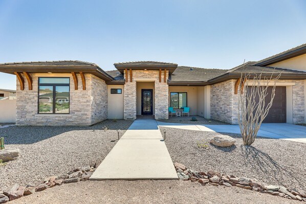 A modern two-story house with a stone facade, a front porch with chairs, and a clear pathway leading to the entrance. - Apache Junction Vacation Rental Heated Pool, Mountain Views, Pet-Friendly Home (Apache Junction)