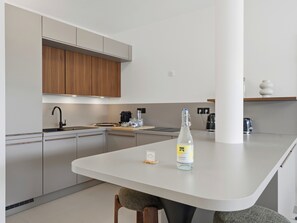 A modern kitchen with a central island, a coffee machine, and a bottle of lemonade.
