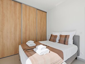 A modern bedroom with a bed, pillows, and a neatly folded towel on the bed.