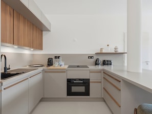 Eine moderne Küche mit eingebautem Ofen, einer Kaffeemaschine und einem Wasserkocher auf der Arbeitsfläche.