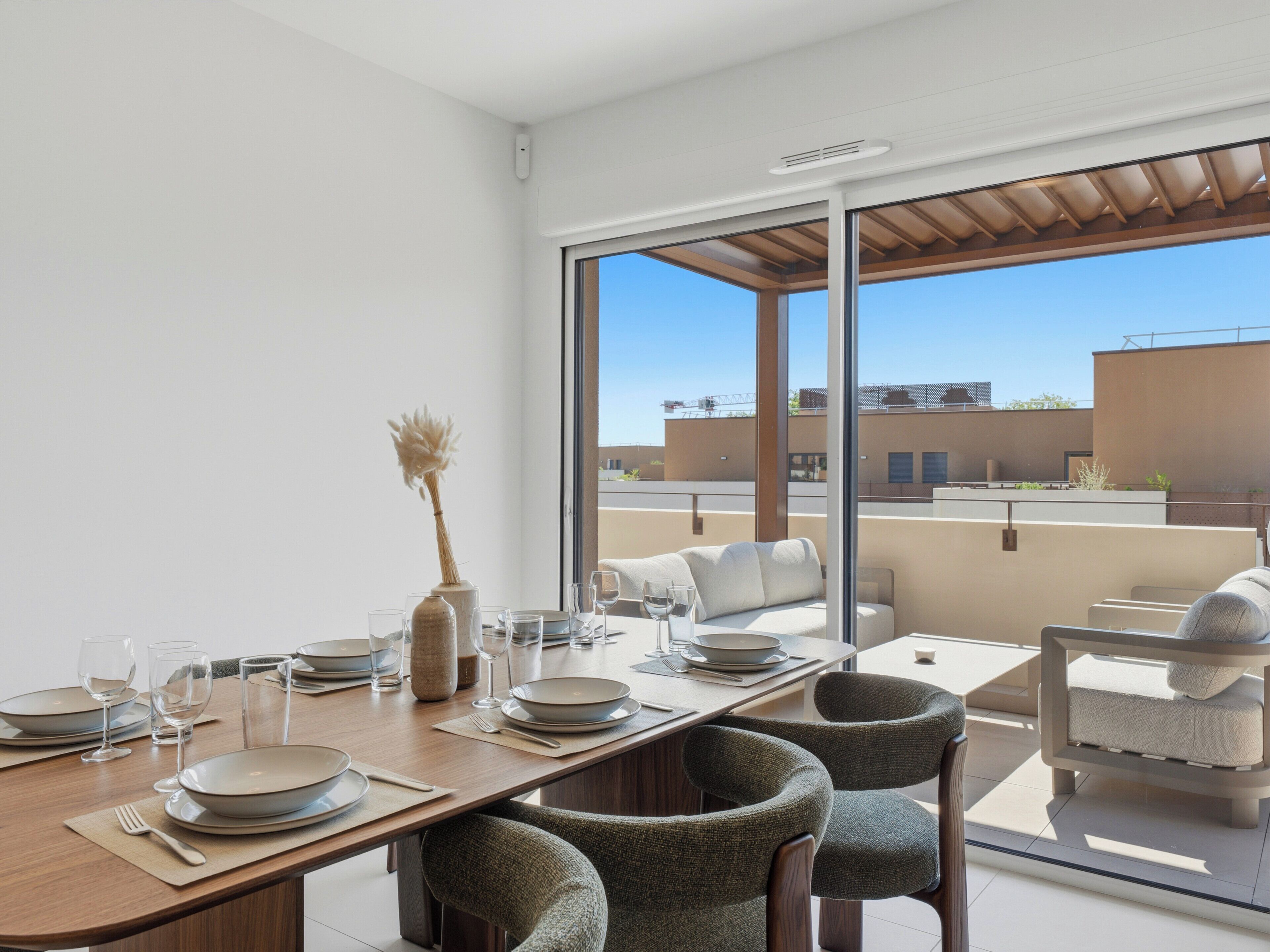 Ein moderner Essbereich mit Holztisch, gedeckt für eine Mahlzeit, große Fenster mit Blick auf die Stadt und ein Balkon mit Sitzgelegenheit.
