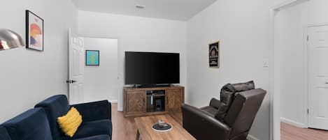 Un salon comprenant un canapé, un fauteuil inclinable, une table basse, un téléviseur et un meuble.