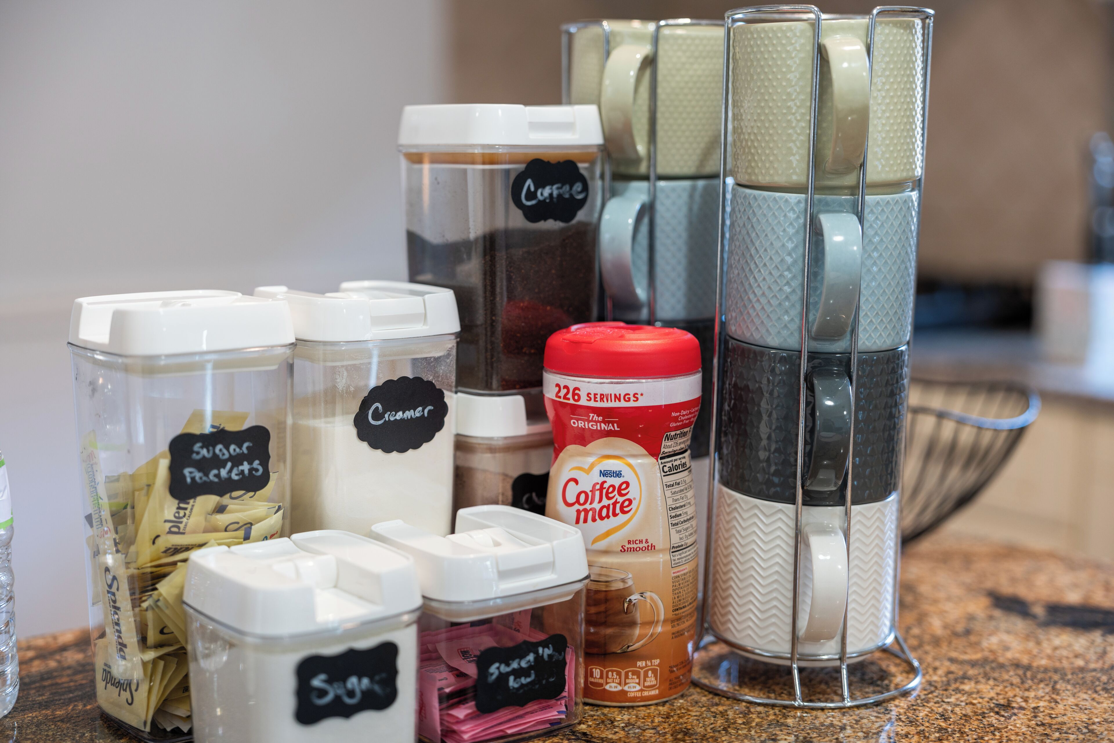 Eine Küchenarbeitsplatte mit verschiedenen Kaffeuzubereitungsmitteln, darunter Zuckerportionen, Sahne und eine Kaffeemaschine.