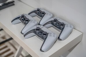 Vier graue Spielcontroller auf einer weißen Oberfläche.