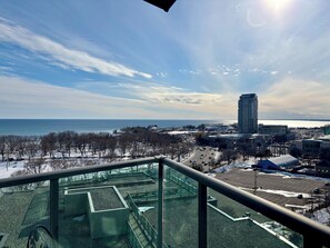 A cityscape with a view of the sea, buildings, and a parking area. - Sundrenched 2 BDRM waterfront gem with lake view near CNE, BMO Field (Toronto)