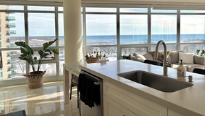 A modern kitchen with large windows, a sink, and a view of the sea. - Sundrenched 2 BDRM waterfront gem with lake view near CNE, BMO Field (Toronto)
