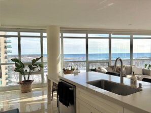 A modern kitchen with large windows, a sink, and a view of the sea. - Sundrenched 2 BDRM waterfront gem with lake view near CNE, BMO Field (Toronto)