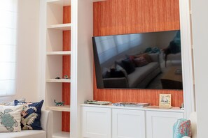 A living room with a large flat-screen TV mounted on a wall, surrounded by white shelving units with various decorative items. - 4BR Luxury Villa, Private Pool + Terrace in Las Catalinas (Guanacaste Province)