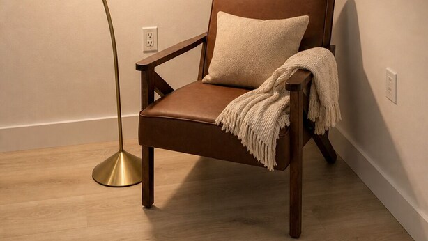 Una silla con una manta, una lámpara de pie y un enchufe de pared.