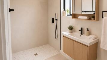 A modern bathroom with a walk-in shower, a vanity with a mirror, and a small window.