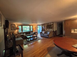 Ein geräumiges Wohnzimmer mit Holzdielenböden, zwei Sofas, einem Couchtisch und einem Esstisch.