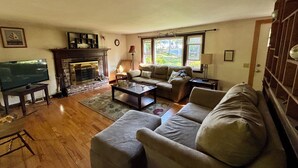 A living room with a fireplace, a television, and a sofa. - Enjoy the best of Cape Cod. Perfect. Private.Parking. Pets. Available Sept 1 (Dennis)