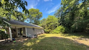 A house with a covered porch, a lawn, and surrounding trees. - Enjoy the best of Cape Cod. Perfect. Private.Parking. Pets. Available Sept 1 (Dennis)