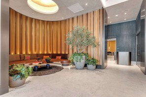 A modern interior with a curved seating area, a large potted plant, and a sleek reception desk. - Miami Pulse With Resort Amenities (Miami)