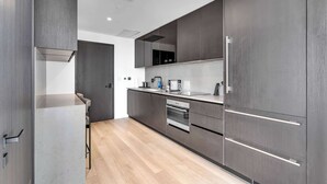 A modern kitchen with dark cabinetry, a stainless steel refrigerator, and a built-in oven. - Miami Pulse With Resort Amenities (Miami)