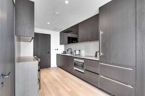 A modern kitchen with dark cabinetry, a stainless steel refrigerator, and a built-in oven. - Miami Pulse With Resort Amenities (Miami)