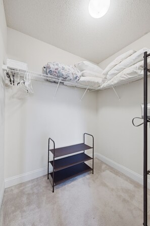 A small, carpeted room with a bunk bed, a metal shelf unit, and a ceiling fan. - Welcome to The Amsterdam Place. (Madison)