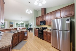 A kitchen with wooden cabinets, stainless steel appliances, granite countertops, and a view of the outdoors. - Welcome to The Amsterdam Place. (Madison)